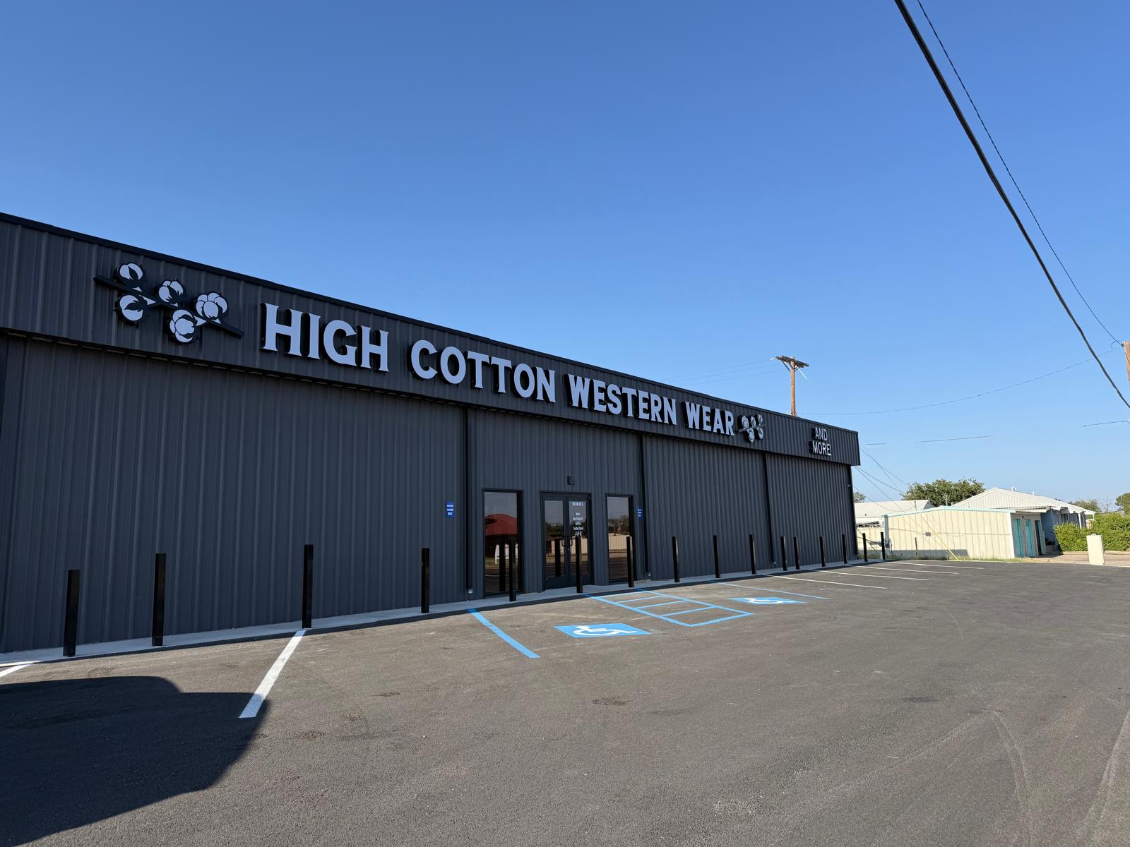 High Cotton Western Wear storefront — a commercial metal building with charcoal siding and accessible parking in West Texas