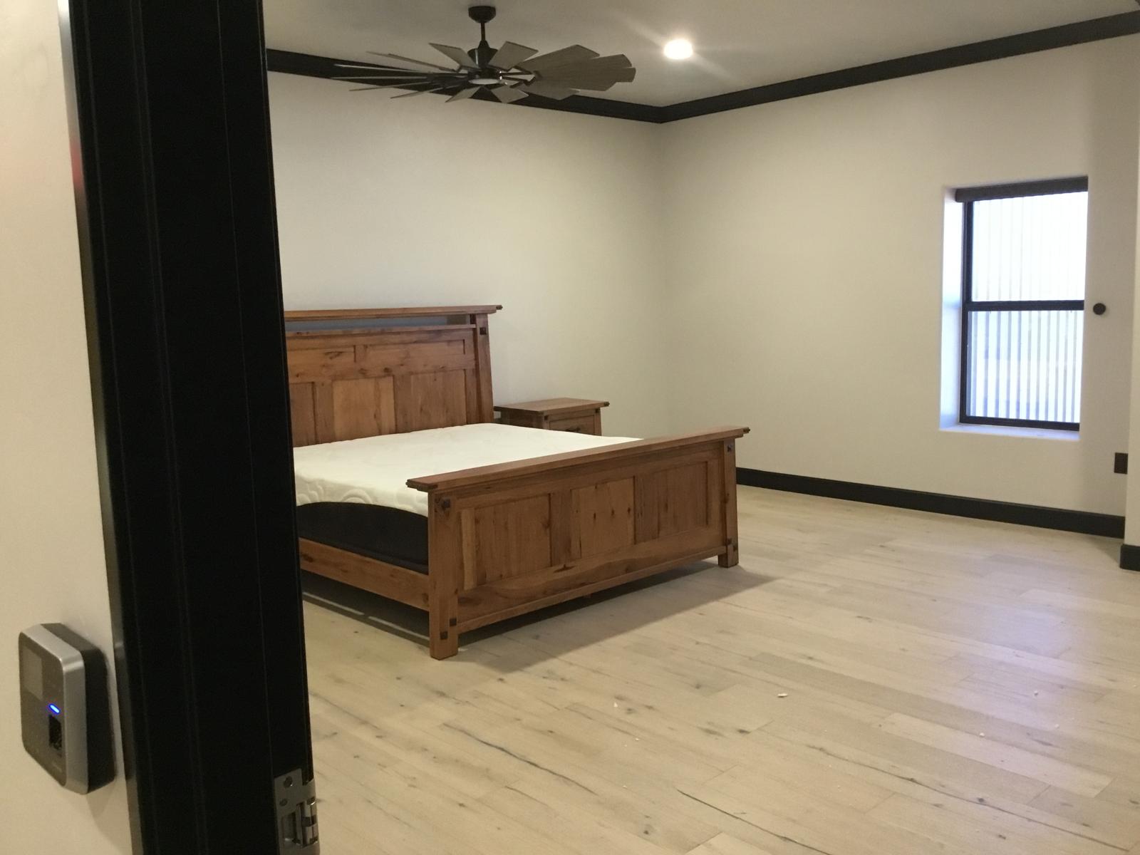 Finished bedroom interior with wood bed frame and ceiling fan inside a metal building